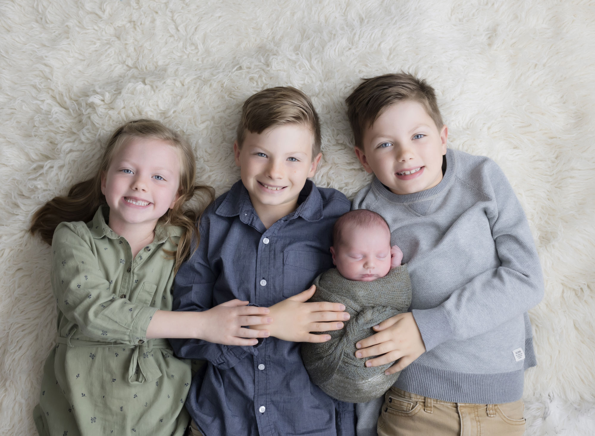 big siblings holding baby brother