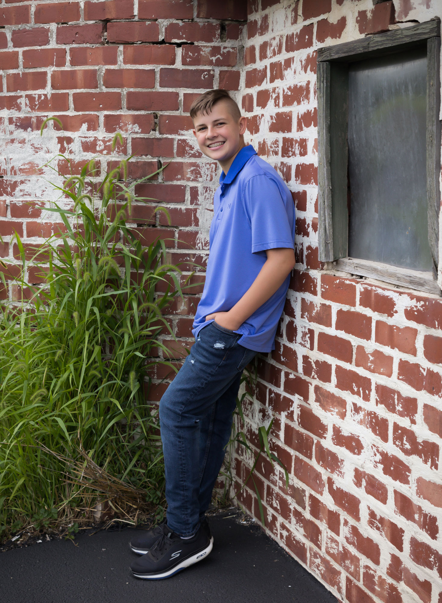 high school boy leaning against brick barn