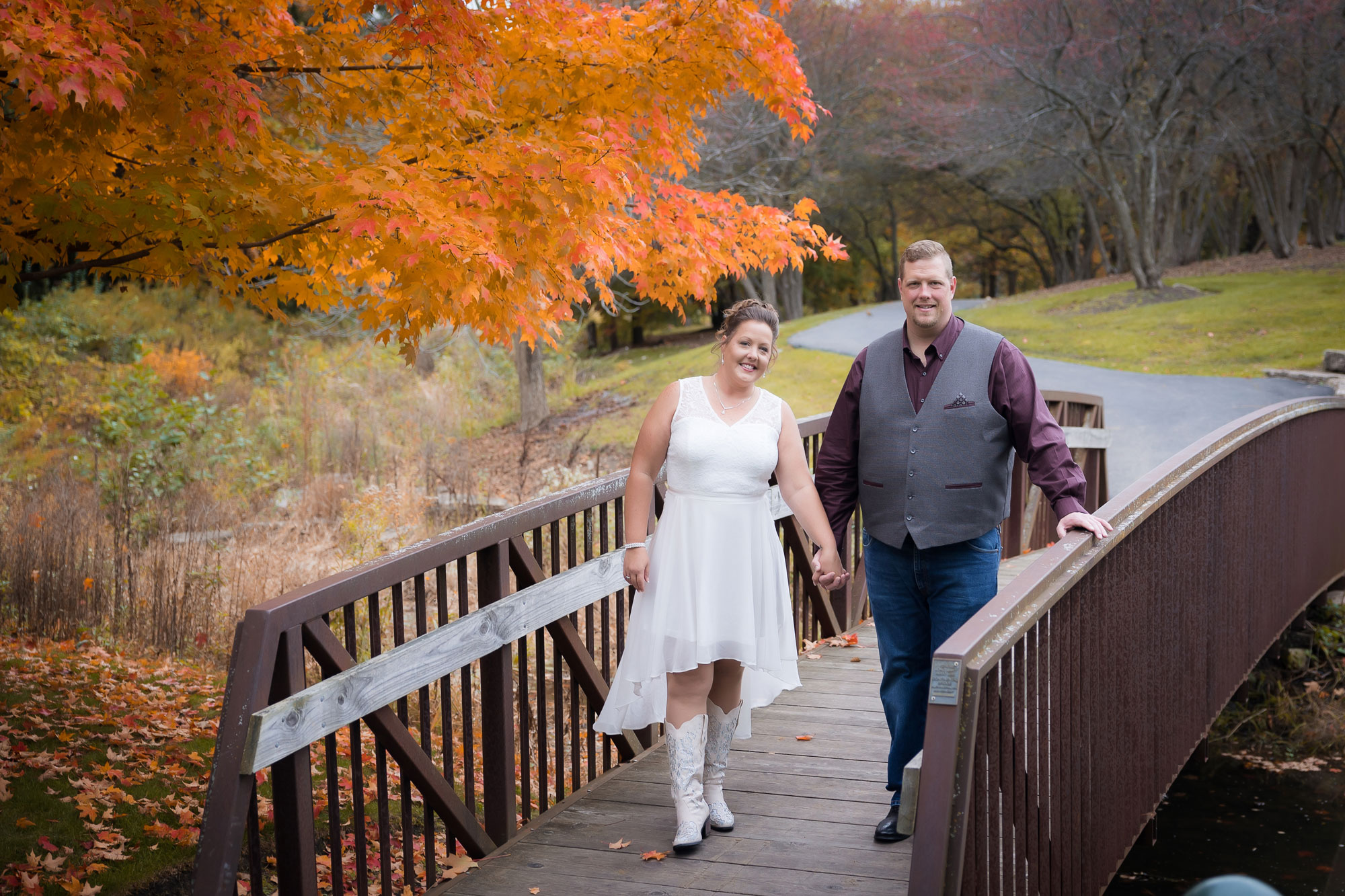 married couple standing on bridge in fall