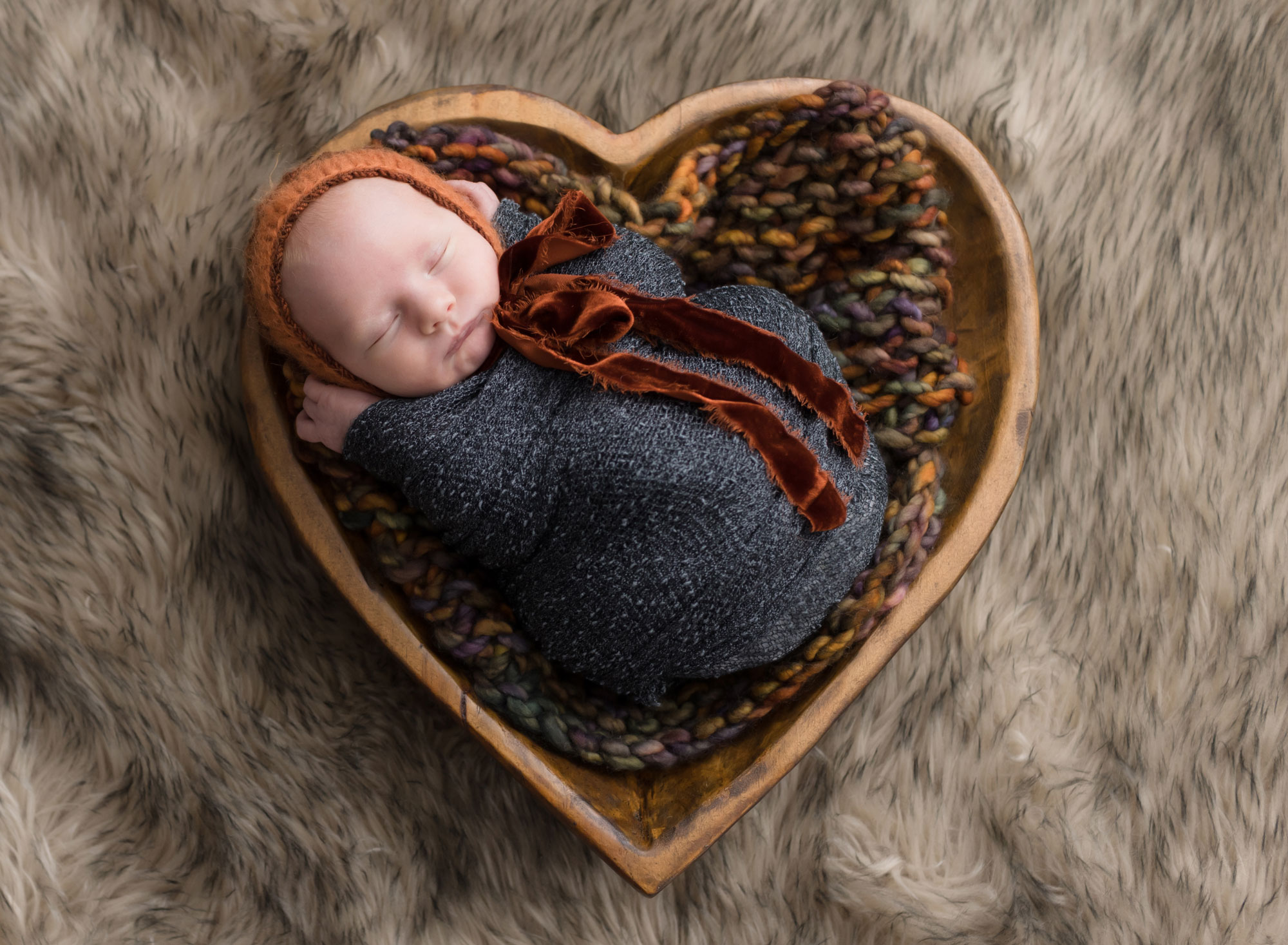 newborn baby in heart shaped bowl