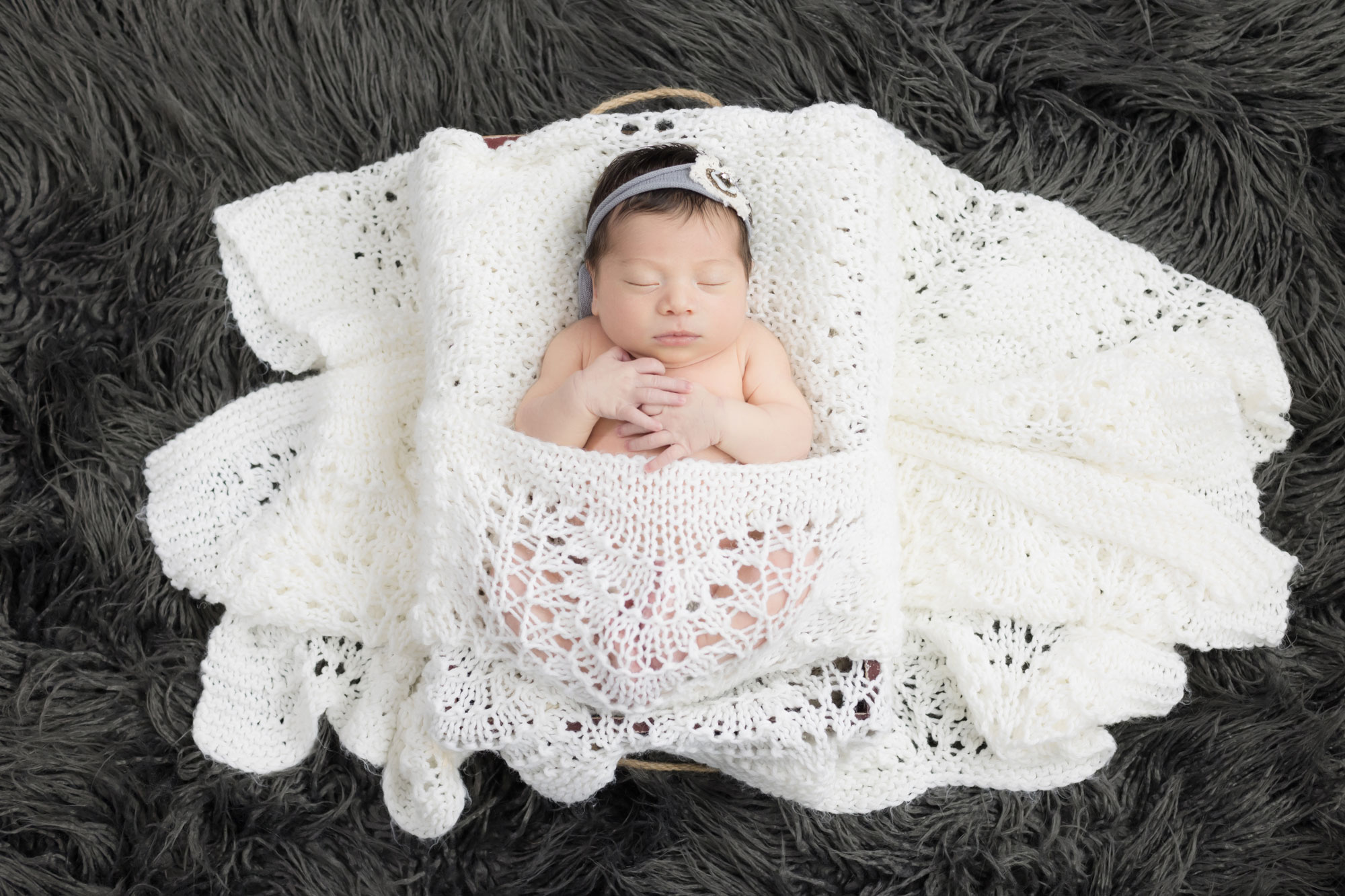 newborn girl sleeping in white knit blanket
