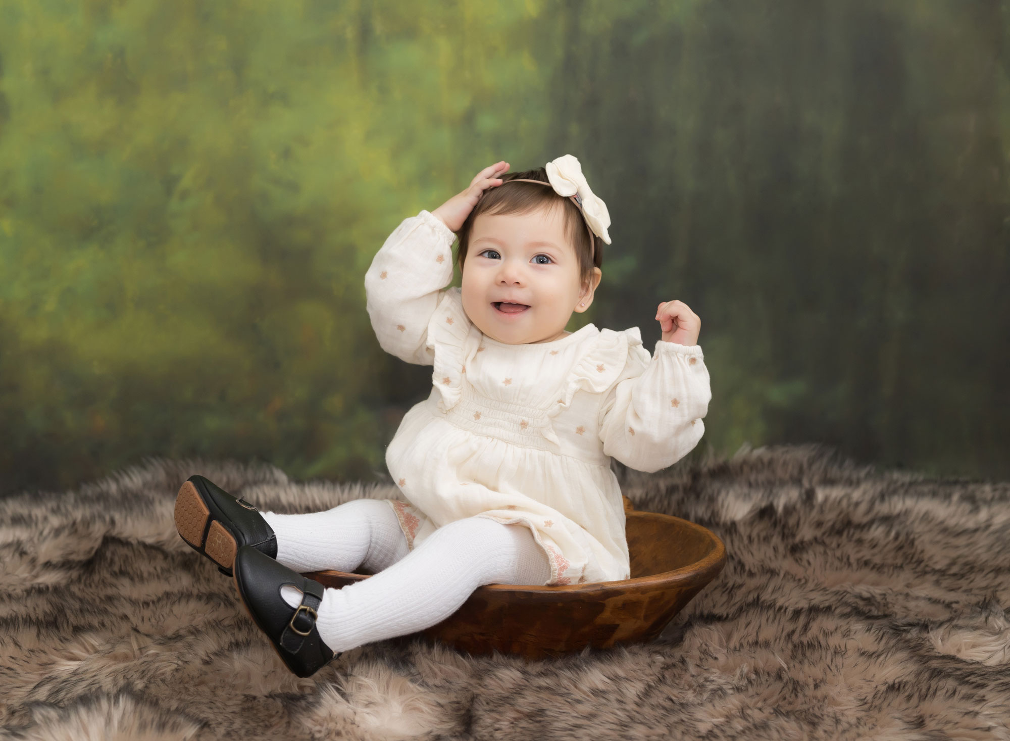 one year old girl sitting in wooden bow