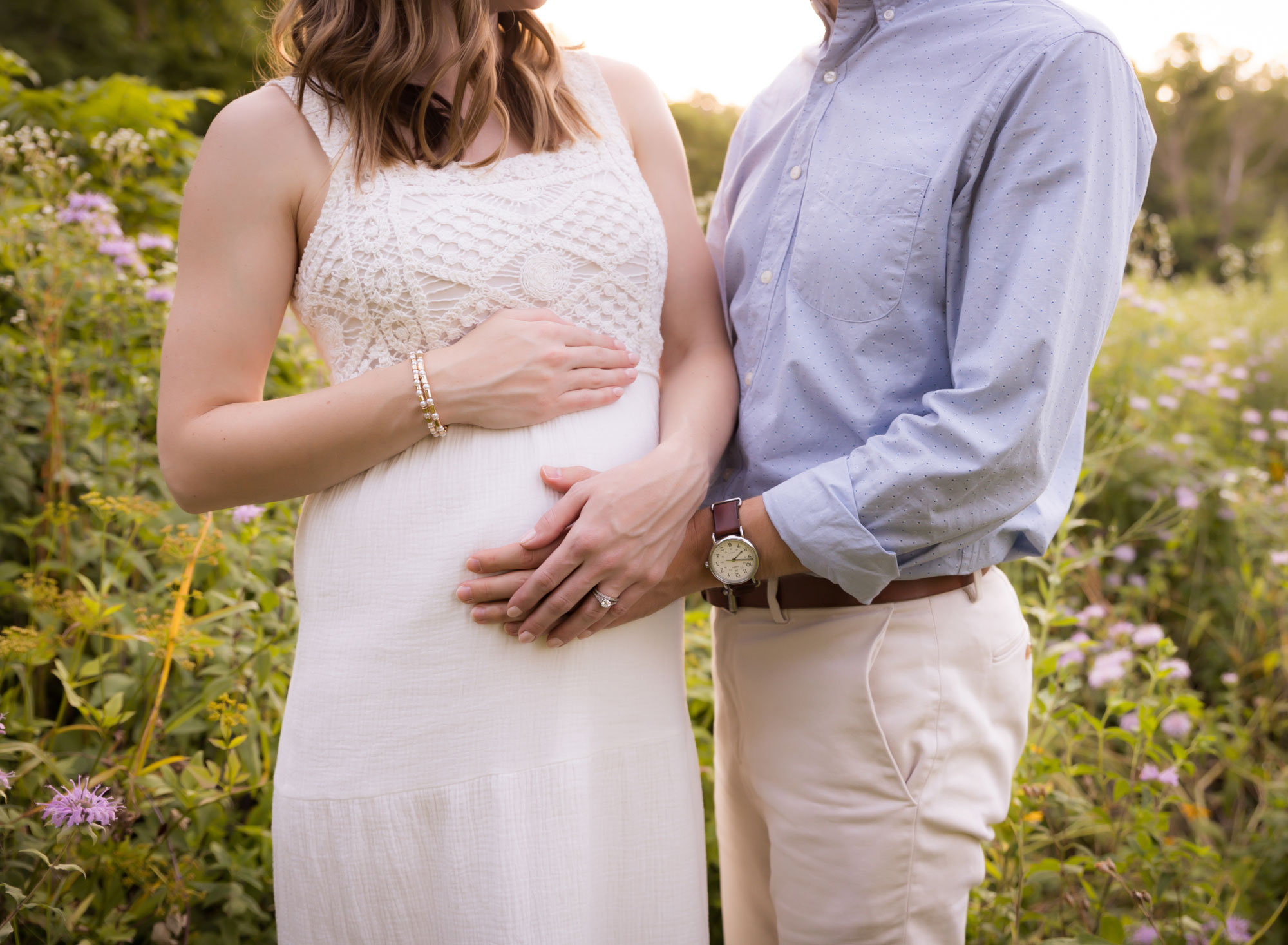 pregnant couple embracing hands on belly