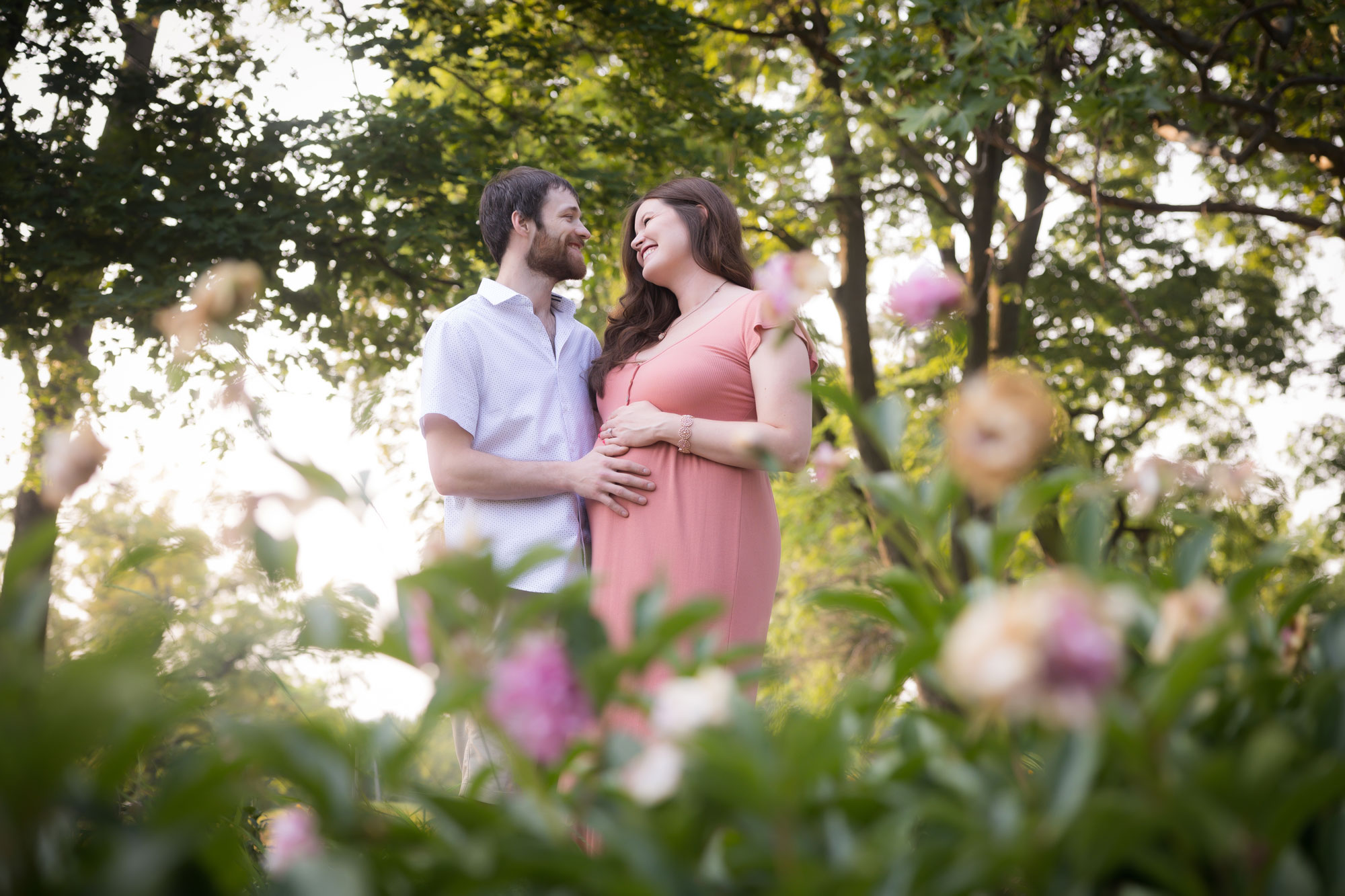 pregnant couple gazing at eachother with flowers in foreground
