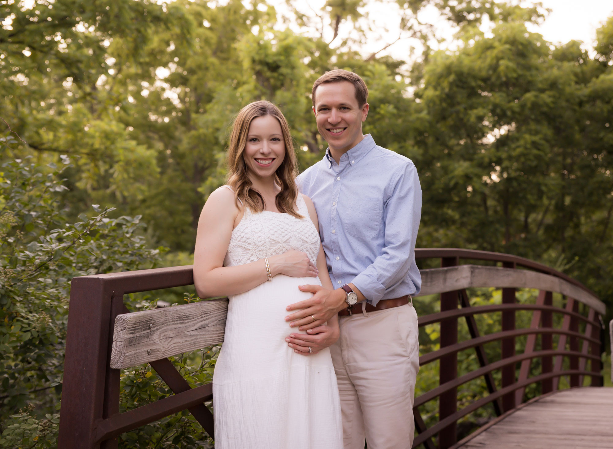 pregnant couple standing and smiling at camera