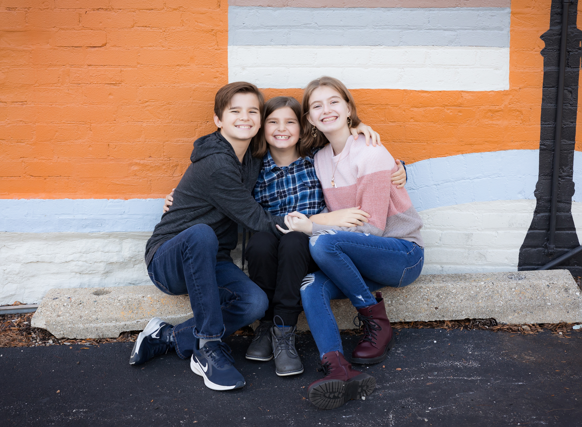 three-kids-hugging-in-front-of-bright-colored-wall