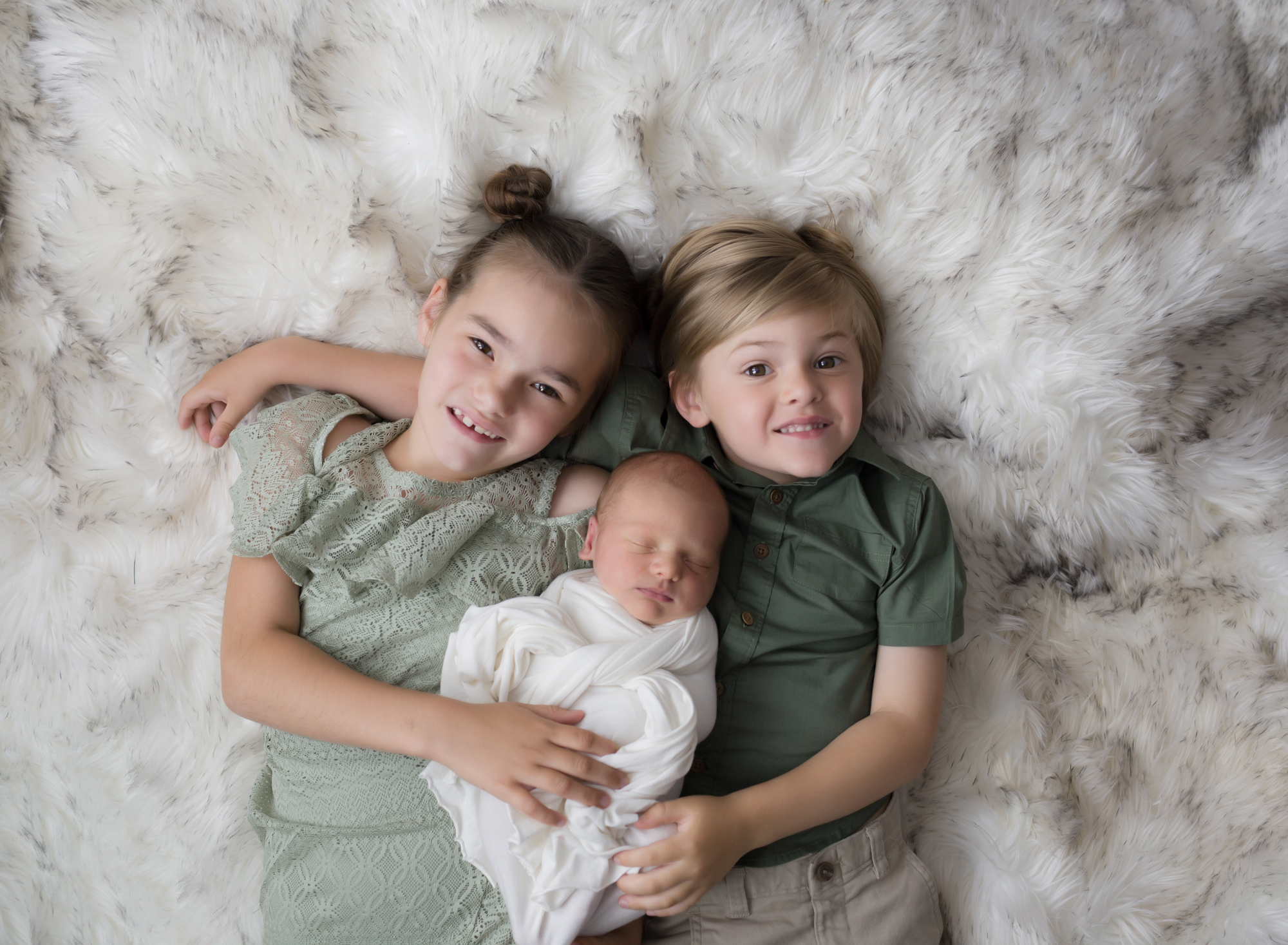three-siblings-snuggling-on-white-fur-rug
