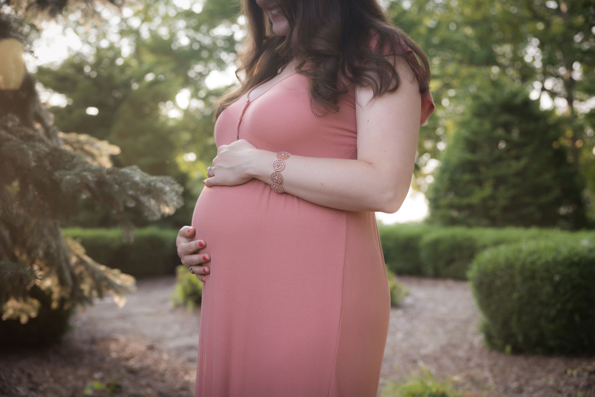 woman in pink holding pregant belly
